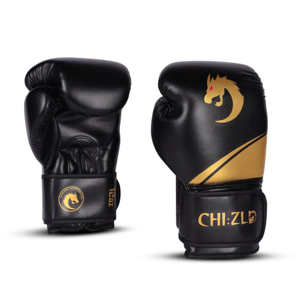 Pair of black/gold chizld boxing gloves, one palm-side and one knuckle-side; matte gold dragon emblem and swoosh accent on striking surface, CHIZLD logo on wrist straps.