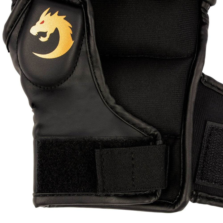Macro of thumb-side padding and Velcro tab, emphasizing raised golden dragon icon on smooth black surface.