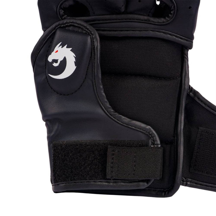Macro of thumb-side padding and Velcro tab, emphasizing raised white dragon icon on smooth black surface.