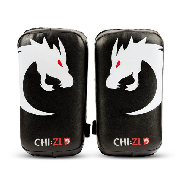 Front view of paired black rectangular kick pads featuring large white dragon-head graphic with red eye and CHIZLD logo at bottom.