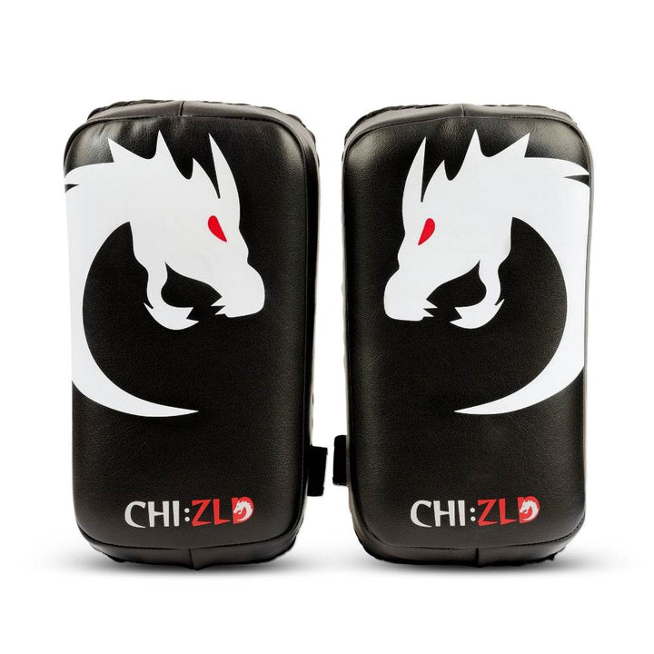 Front view of paired black rectangular kick pads featuring large white dragon-head graphic with red eye and CHIZLD logo at bottom.