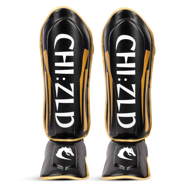 Front view of both shinguards standing upright: large vertical CHIZLD lettering on shin panels, white dragon logos on instep pads.