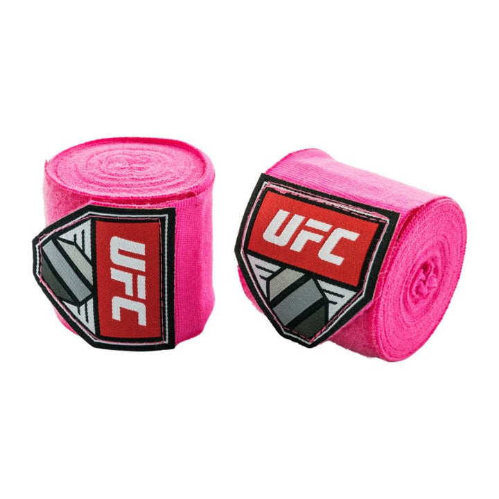 Pair of rolled UFC hand wraps in vibrant hot-pink fabric; contrasting red UFC shield logo patches centred on each roll.	