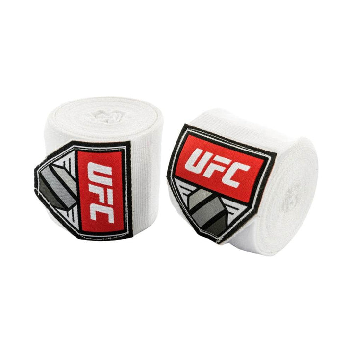 Pair of rolled UFC hand wraps in clean white fabric; red UFC shield logos create a striking contrast on each roll.