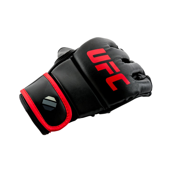 Hero angle – Glove resting at three-quarter view; glossy black finish, red logo and octagon emblem on strap pop against white backdrop.