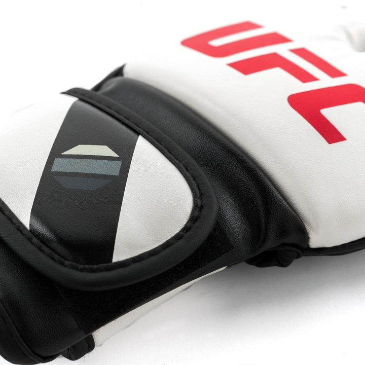 Macro of strap tab: matte white panel bisected by black stripe with three-tone octagon mark, neatly top-stitched border.
