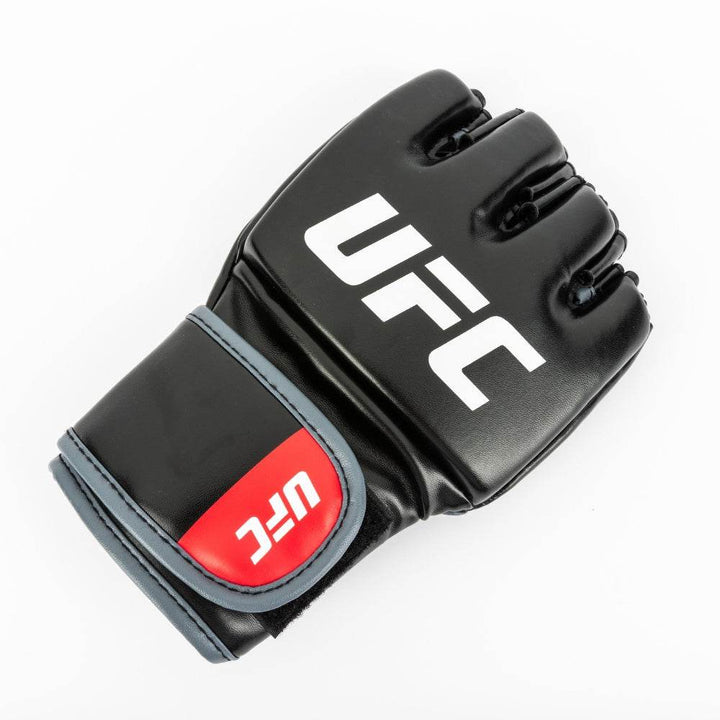 Three-quarter shot of glove lying flat; red branding and red strap trim pop against dark body and white backdrop.