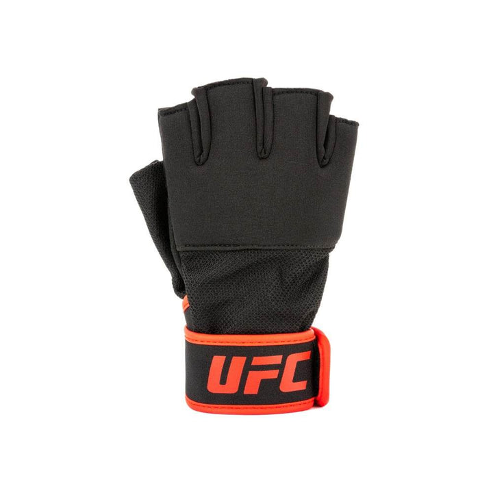 Single glove – knuckle side: One black UFC weight-lifting glove stood upright, knuckle side facing camera. Red-trimmed wrist strap wraps across the wrist with the red “UFC” word-mark centred.