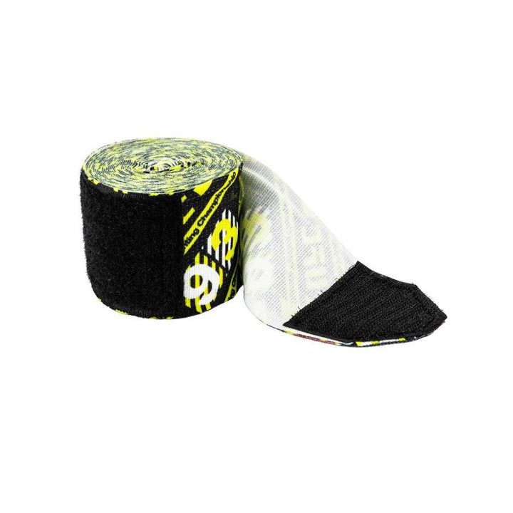 Roll of the hazard-pattern hand wrap with several centimetres unrolled, revealing the white printed inner face and black hook-and-loop closure end.