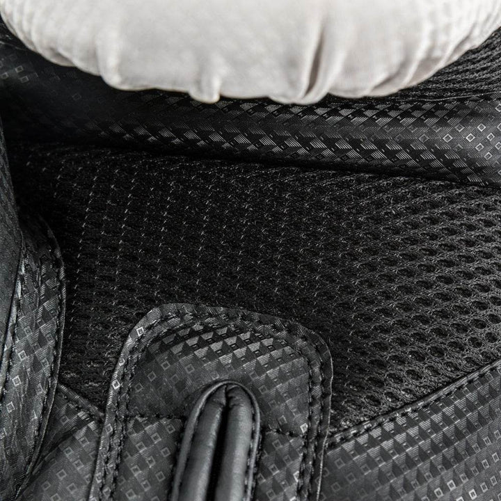 Close-up of the interior wrist cuff on a white-and-black UFC Performance Rush boxing glove, displaying the soft moisture-wicking lining, finger gusset stitching, and the black hook-and-loop strap folded back to reveal the padded underside.