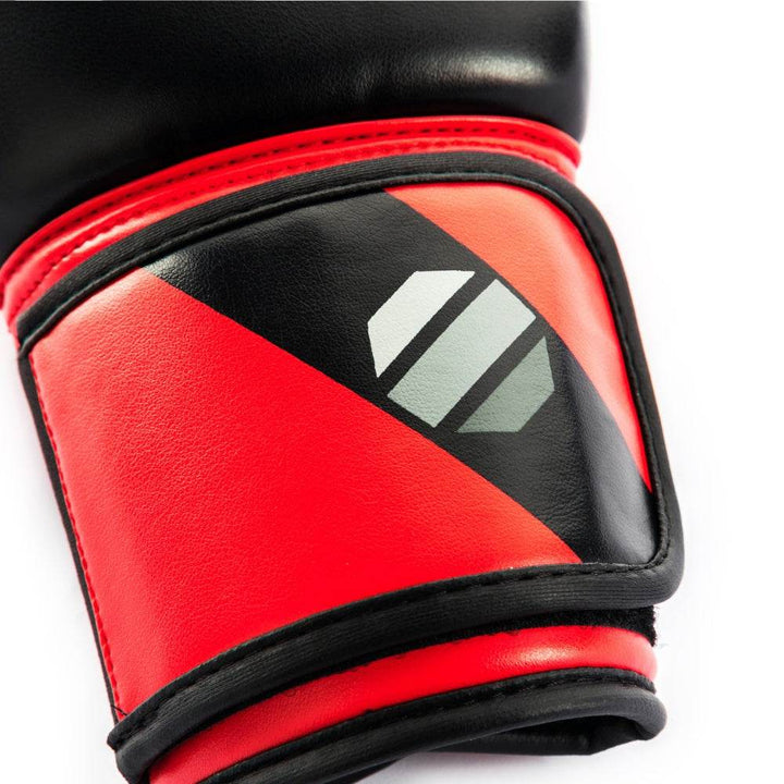 Close-up detail of the wrist cuff on a red-and-black UFC Pro Compact bag glove, showing the padded red strap with an embossed octagon logo, reinforced stitching.
