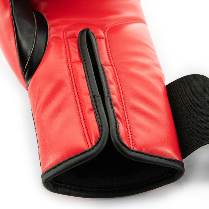 Close-up of the interior wrist cuff on a red-and-black UFC Pro Compact bag glove, showing the soft moisture-wicking black lining, reinforced red stitching, and the underside of the red hook-and-loop strap folded back to reveal the padded wrist support.