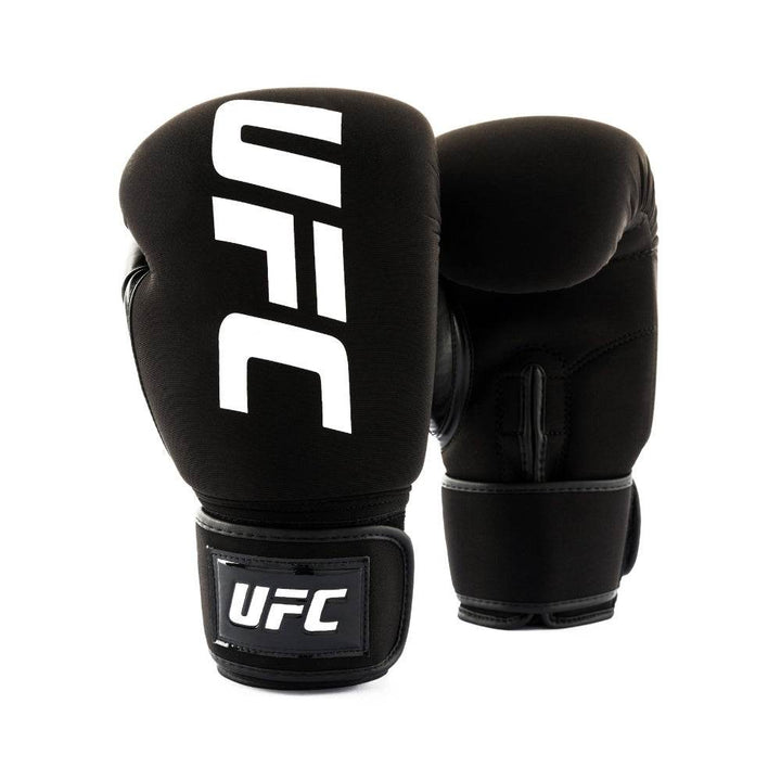 Front three-quarter view of a pair of all-black UFC Pro Washable bag gloves: lead glove faces forward with large white vertical “UFC” logo while the rear glove shows the thumb side and wrist-loop detail.