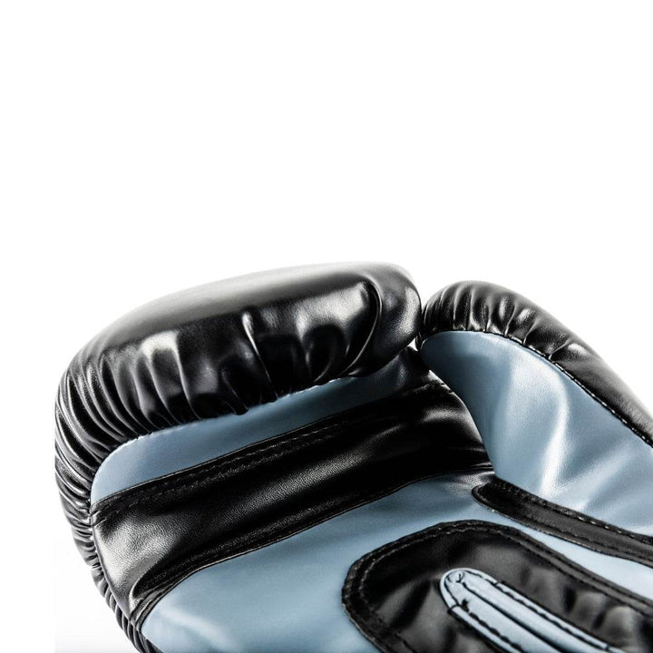 Macro shot of the palm side near the thumb, focusing on the glossy black leather padding, blue synthetic insert and reinforced stitching.