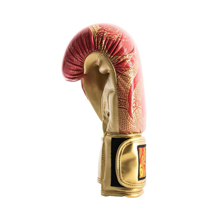 Angled side profile of a red UFC Thai Naga boxing glove lying on its outer edge, highlighting the curved striking surface with black Naga-scale graphic, stitched thumb attachment, and partially opened black hook-and-loop wrist strap.