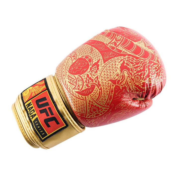 Close-up of the red UFC Thai Naga boxing glove’s knuckle surface, highlighting the black serpent-scale pattern printed on smooth synthetic leather and the fine grain texture of the red material.