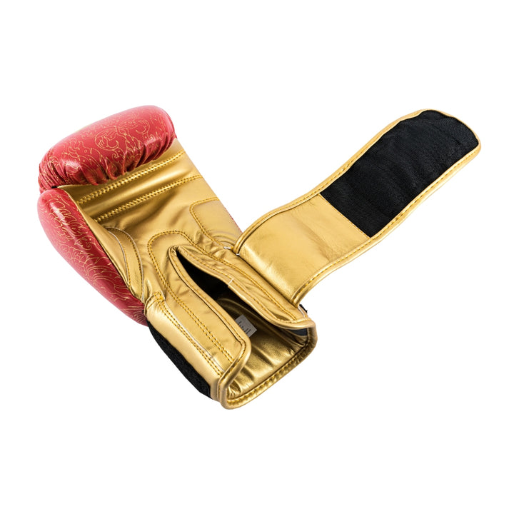 Palm-side view of a red UFC Thai Naga boxing glove with the black hook-and-loop wrist strap fully extended, revealing the ventilated black mesh palm panel, padded thumb channel, and interior lining beneath the red serpent-scale knuckle surface.