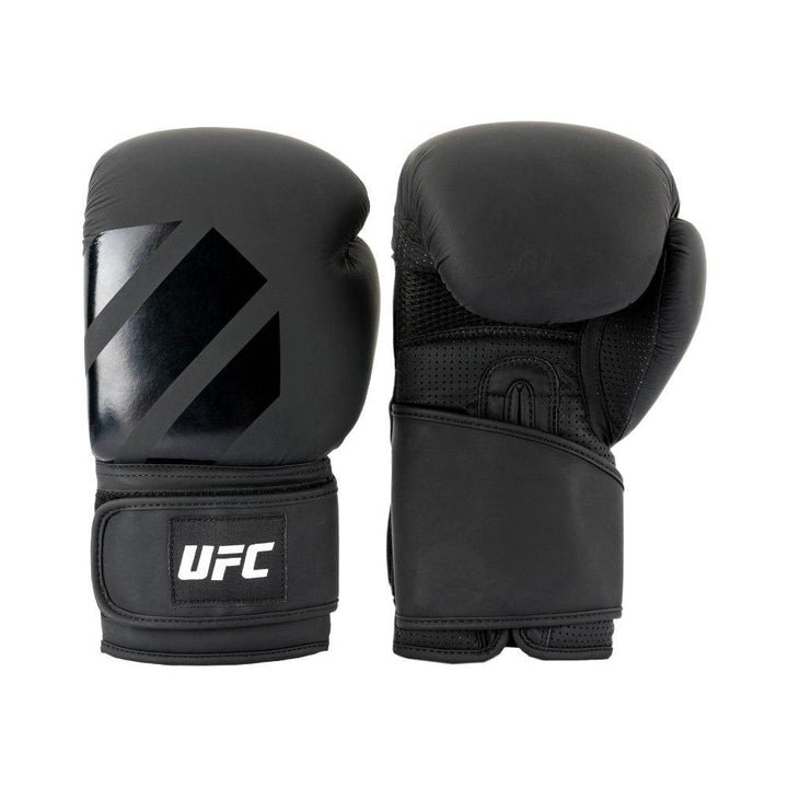 Right-hand glove shows smooth matte-black fist surface with glossy tonal octagon graphic; left glove turned palm-up revealing ventilated mesh panel and layered wrist wrap.