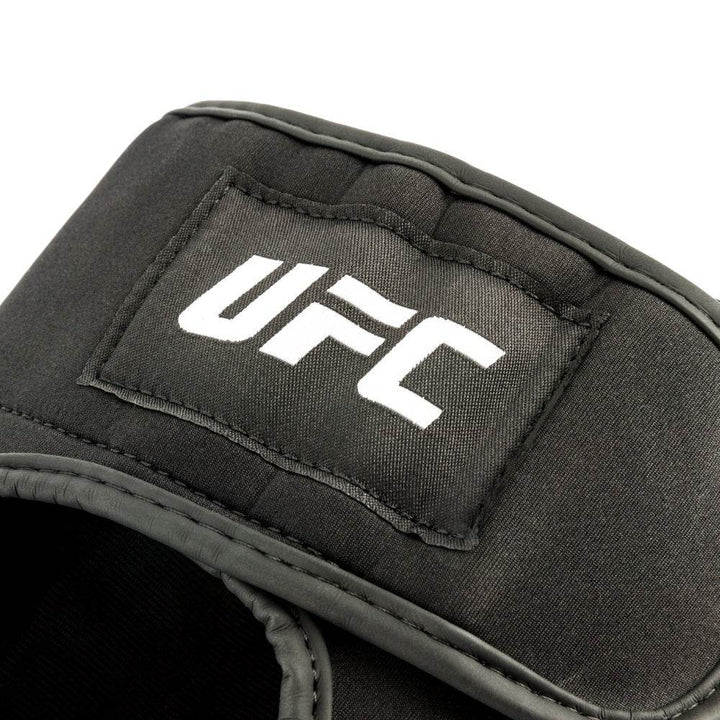 Close-up – top logo patch: Stitch-on rectangular patch with bold white “UFC” word-mark sewn onto the upper rear strap.