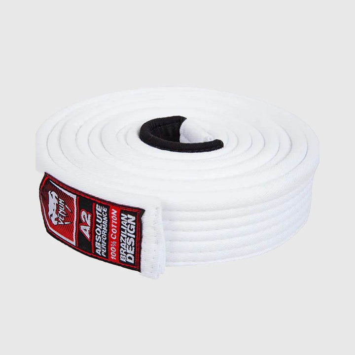 Rolled Venum Brazilian Jiu-Jitsu white belt with black patch and red label showing size A2 and '100% cotton Brazilian design' details.