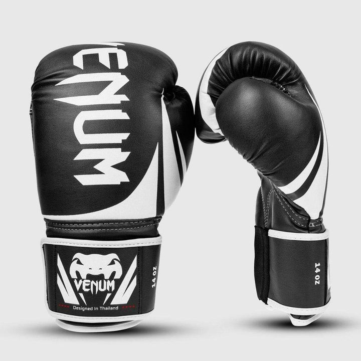 Paired glove view with one glove clenched, emphasizing the curved ergonomic shape and full graphic styling across the black and white color scheme.