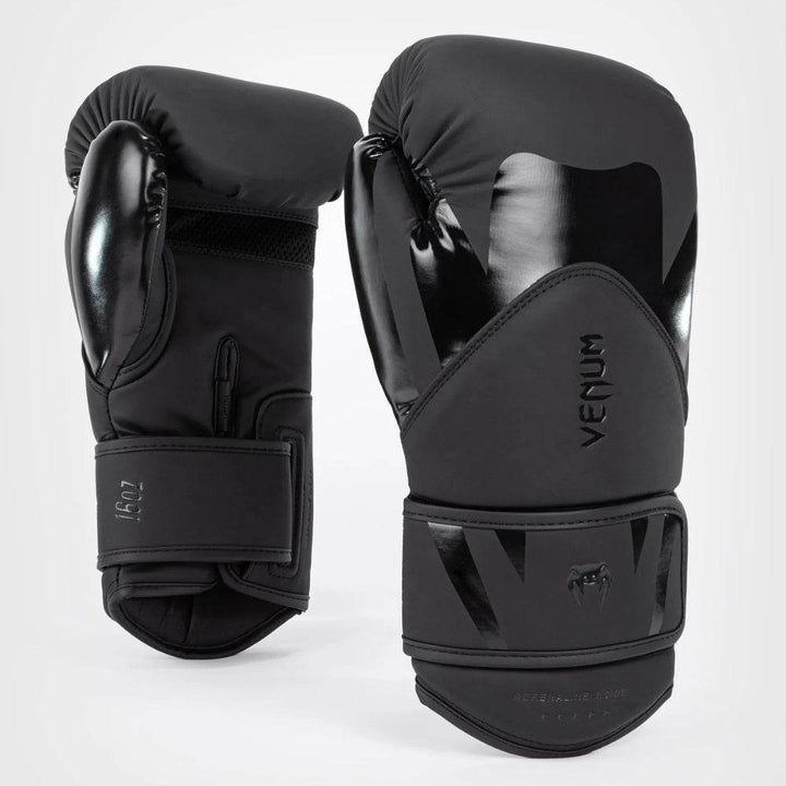 A pair of all-black Venum Challenger 4.0 boxing gloves with a mix of matte and glossy finishes, the Venum logo and “Adrenaline Inside” branding visible.