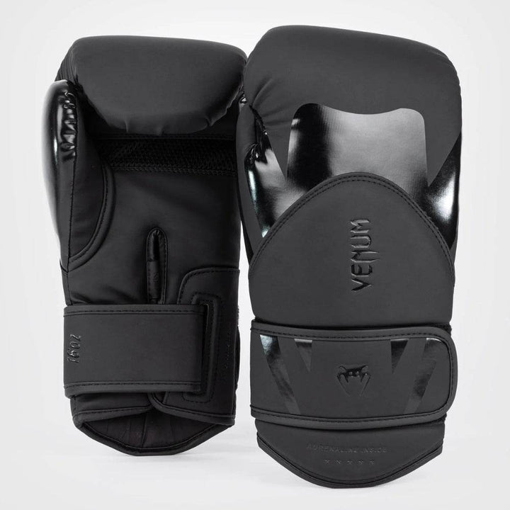 Image showing both gloves from the front and back, emphasizing the glossy black overlays and subtle Venum branding in the front and mesh panel on the palm at the back with velcro wrist strap mechanism.