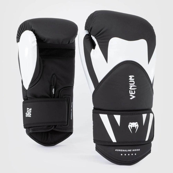 Pair of Venum Challenger 4.0 gloves in black and white colorway, showcasing front and palm sides with bold fang design and white branding.
