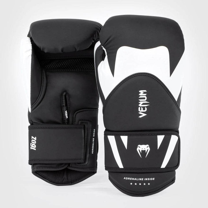 Front-facing and angled views of black and white Venum Challenger 4.0 gloves, emphasizing the shield-style knuckle panel and Adrenaline Inside tagline.