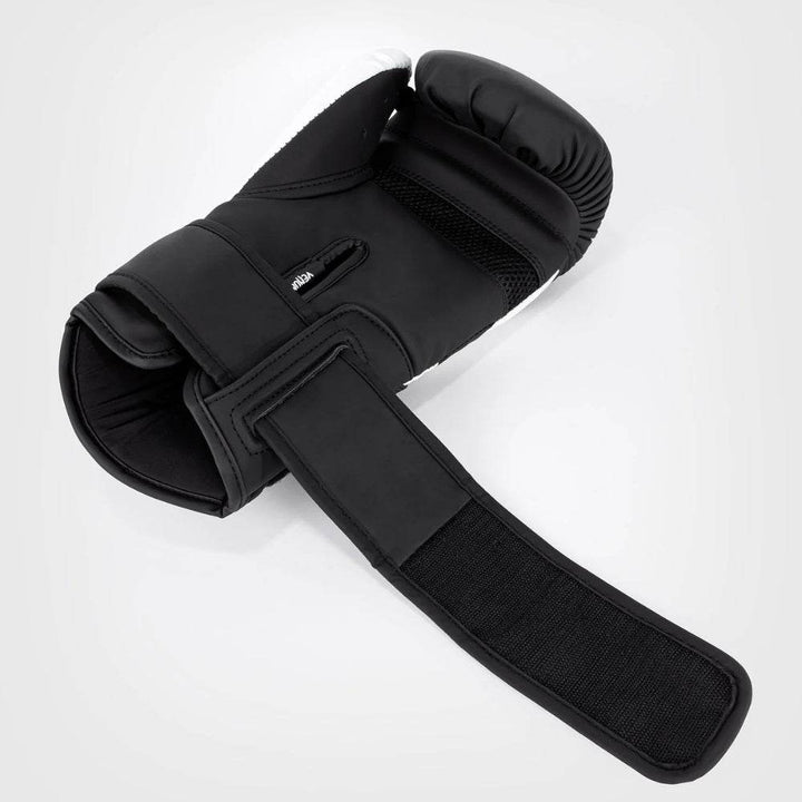 Overhead view of an open black and white Venum Challenger 4.0 glove with velcro strap extended, revealing breathable mesh on the palm.
