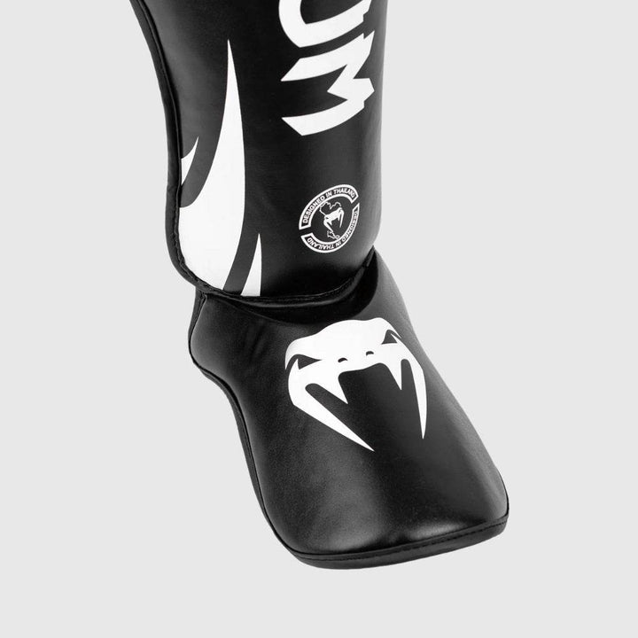 Detailed image of the foot guard area with a prominent white Venum snakehead logo against black synthetic leather padding.