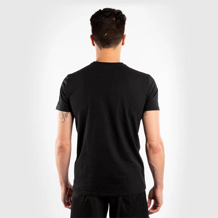 Rear view of the same man wearing the t-shirt, displaying the plain black back without any design.