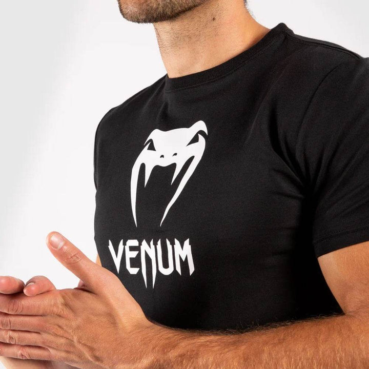 Close-up of the chest area of the black t-shirt showing the white Venum snake logo and brand name.