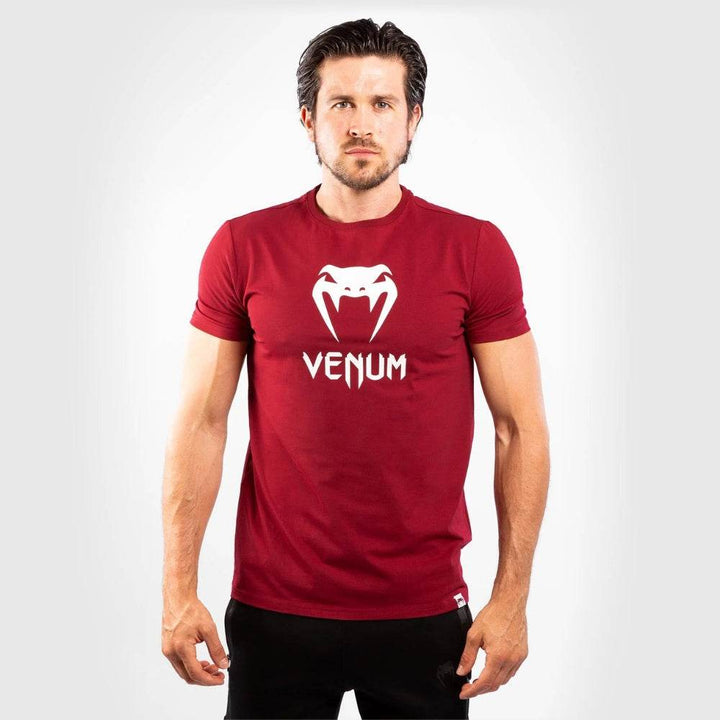 Man facing forward in a red Venum t-shirt with a bold white Venum snake logo and text centered on the chest.