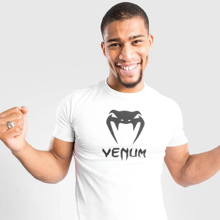 Close-up of a smiling man wearing the white Venum t-shirt with black Venum snake logo.