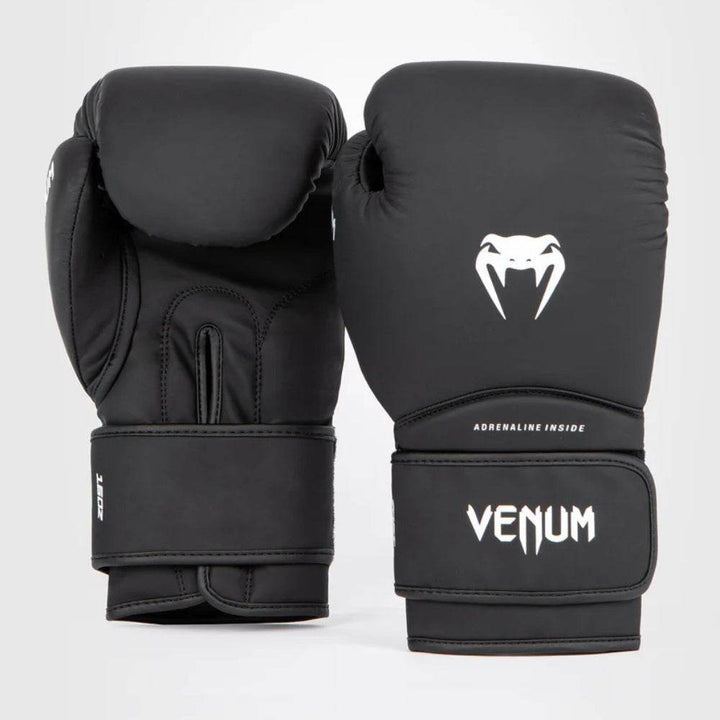 Front and back view of Venum Contender 1.5 boxing gloves in black and white, showcasing the signature Venum snakehead logo in white on the striking surface and “VENUM” text on the wrist strap.