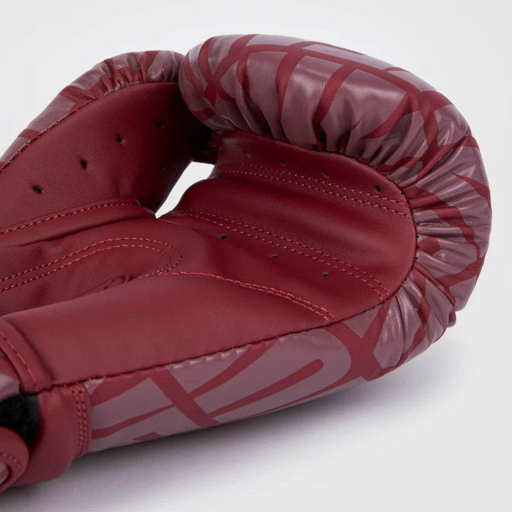 Palm-side angle showcasing interior padding, finger arch, and perforated mesh for breathability with burgundy/white overlay.