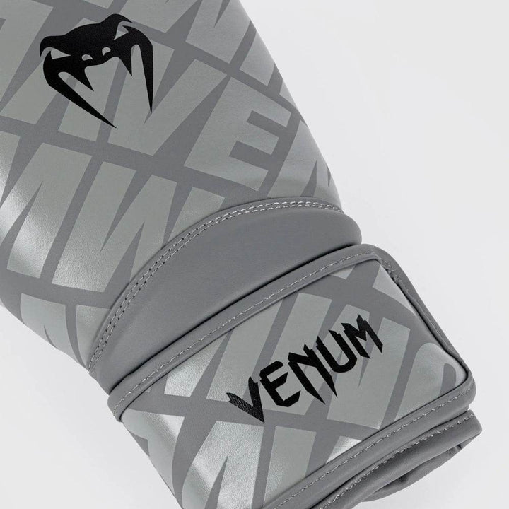 Close-up of the wrist strap on the grey/black gloves featuring the white “VENUM” logo over the diagonal silver-text pattern.
