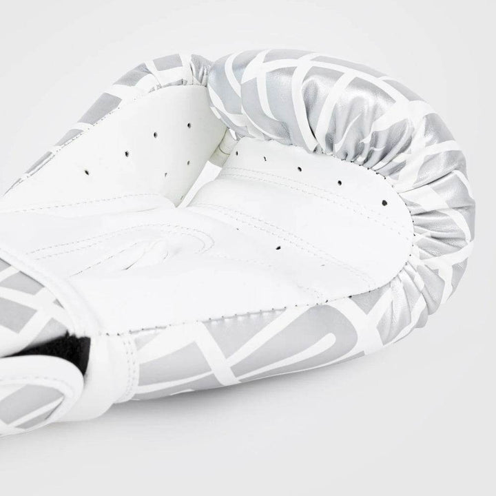 Angled close-up of Venum Contender 1.5XT glove in white and silver, showing metallic text pattern, black snakehead logo, and ergonomic glove curvature.