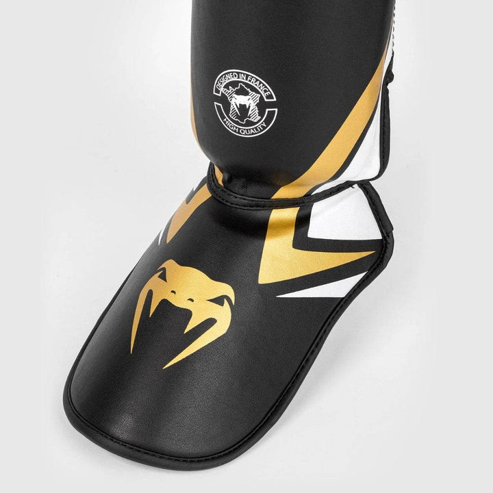Detailed view of the footpad area with a fierce gold Venum snakehead logo over a black base, trimmed with sharp white and gold graphics for added style.