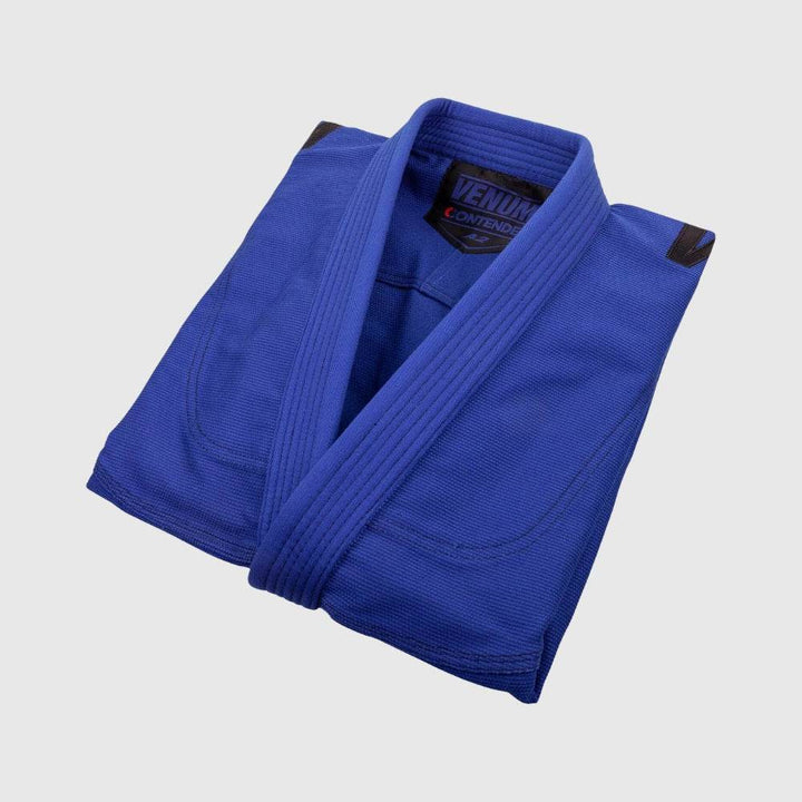 Top-down view of a folded blue gi jacket highlighting the thick lapel stitching and compact storage style.