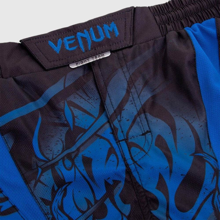 Close-up of front waistband with blue embroidered “VENUM” logo and stitched Velcro tab closure above a small “FIGHT TEAM” metal accent plate.