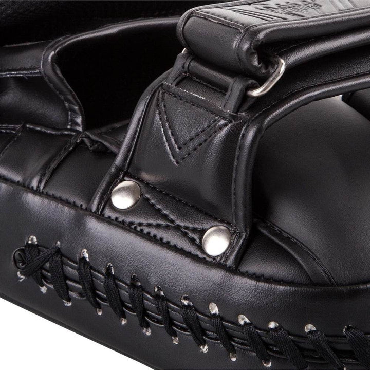 Macro view of the side strap and reinforced stitching with metallic rivets and black lace trim for structural durability.