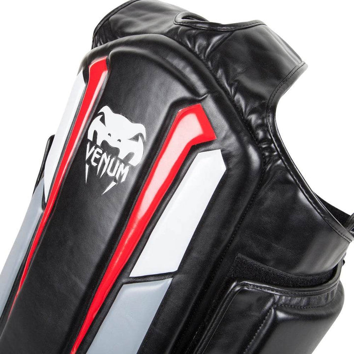 Close-up image of the chest area of the Venum Elite Body Protector showing thick protective foam and the prominent white Venum snake logo.