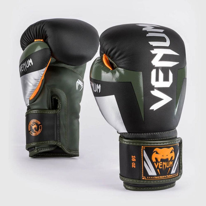 Venum Elite boxing gloves in black, silver, and kaki green with white and orange Venum branding, shown from an angled upright view.