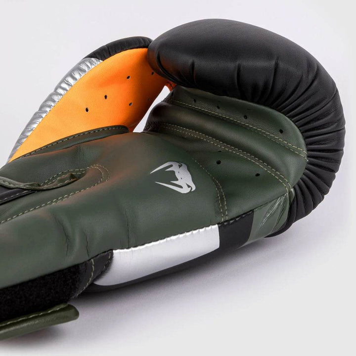 Palm view of the Venum Elite glove showing green leather, silver thumb area, orange inner lining, and ventilation holes.