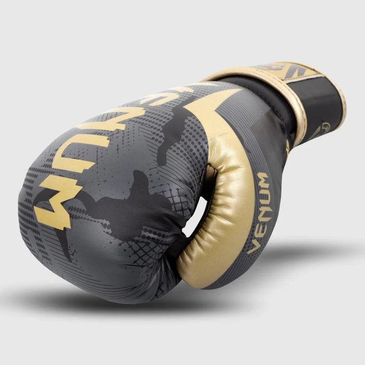 Perspective view of a single glove angled forward, highlighting the curvature and striking camo/gold Venum branding.
