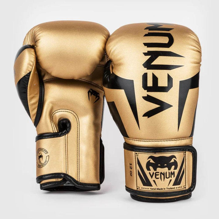 Front view of Venum Elite gloves in gold and black featuring high-contrast gold surface and striking black graphic details.