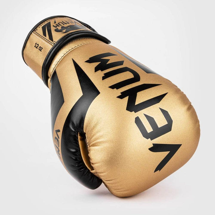Top-down shot capturing the glove’s rounded punch surface and embroidered logo patch on the gold and black wrist wrap.