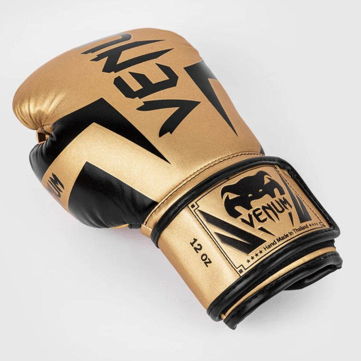 A close-up of the glove’s gold exterior showing the contoured silhouette, thumb protection, and black trim details.